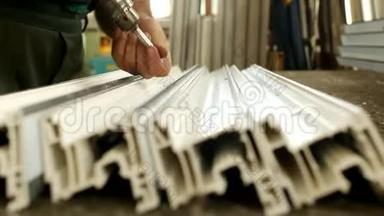 制造窗户pv c，男工在型材pv c中拧螺丝，用于窗户制造，商店和窗户